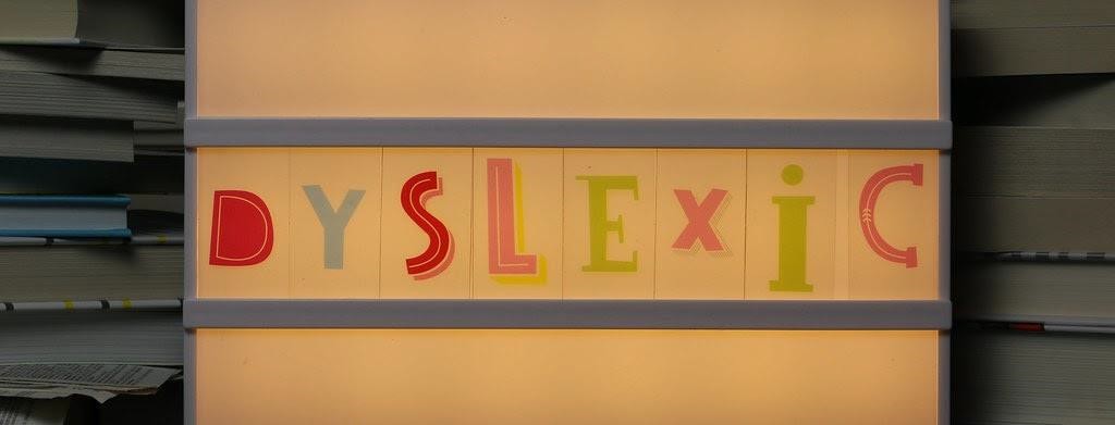 The word Dyslexic written out on top of a light box in stylistic text. Books are stacked either side.